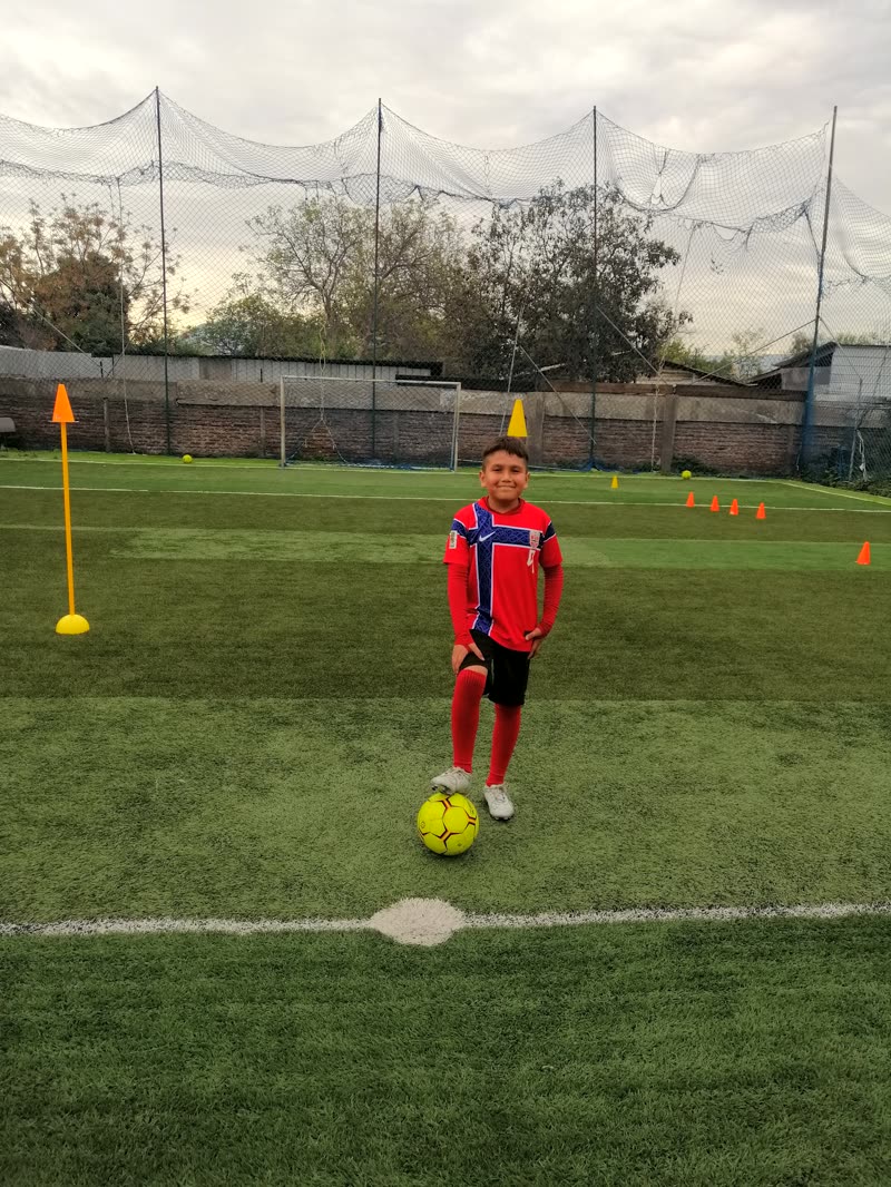 Alumno con camiseta roja preparado con el balón frente a los conos